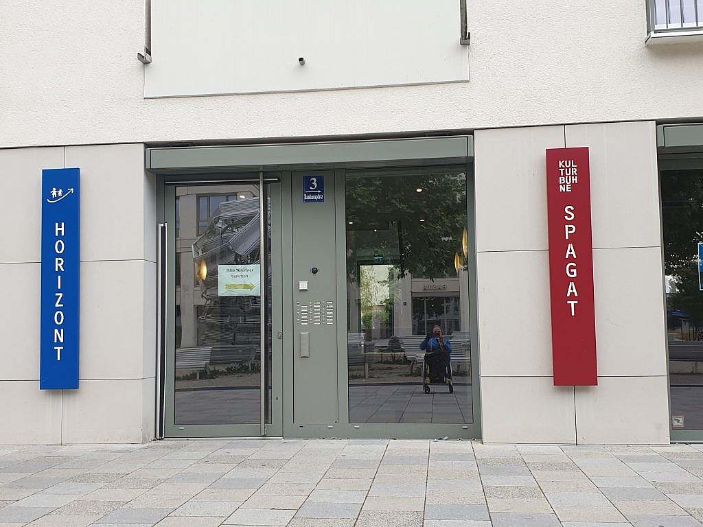 Eingangstüre ebenerdig links davon blaues Schild Horizont rechts davon rotes Schild Kulturbühne Spagat