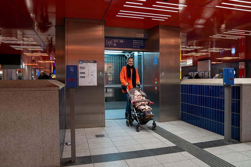 Frau mit Kinderwagen vor offener Aufzugstüre