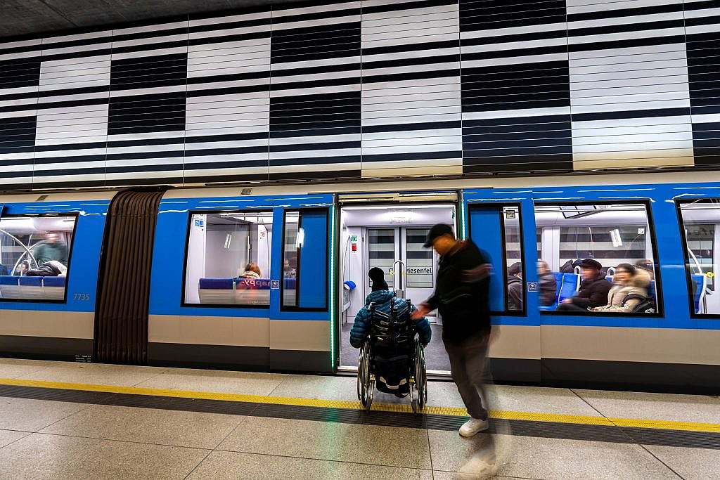 Person in wheelchair and man in front of open subway door