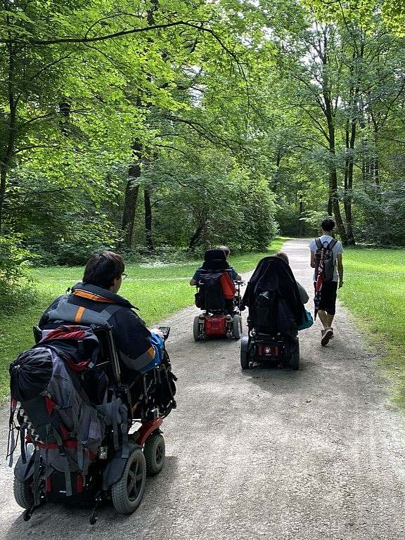 Wheelchair group and pedestrian on paved path in park