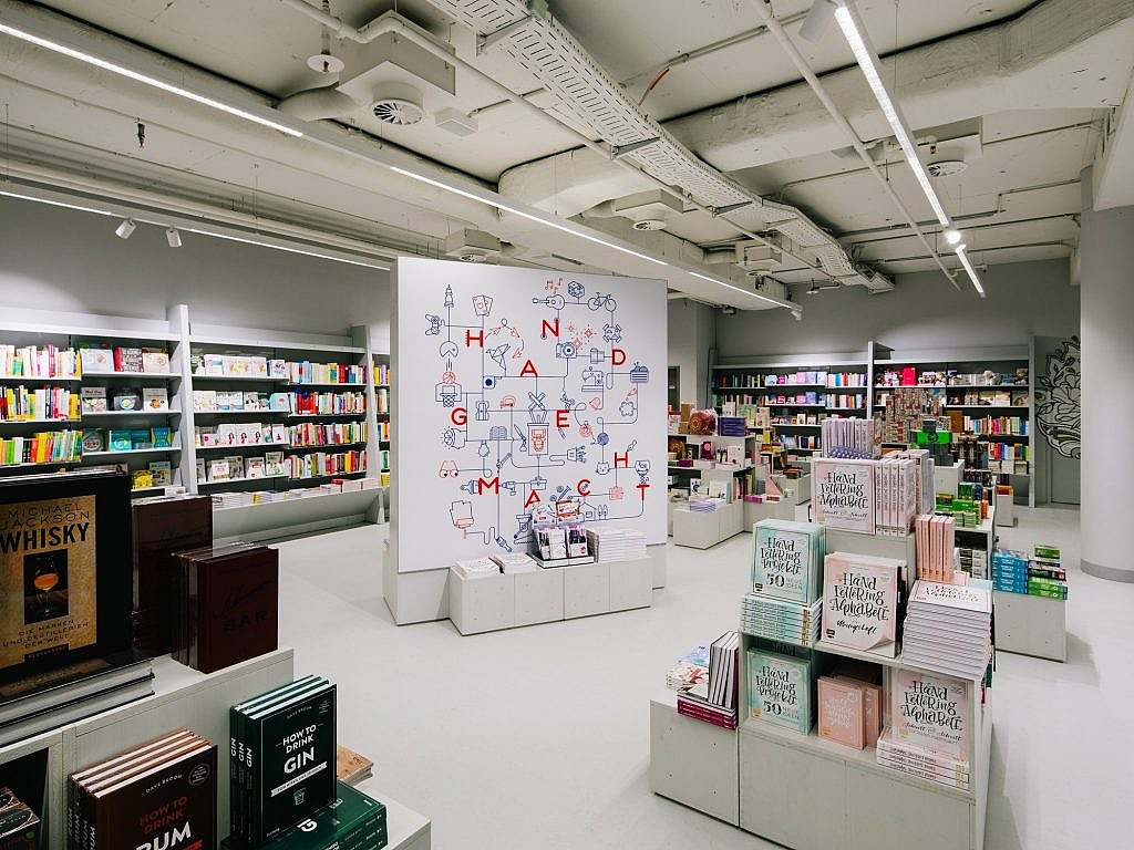 Ein großer Raum mit mehreren Bücher-Inseln und Bücheregalen über die ganzen Wände