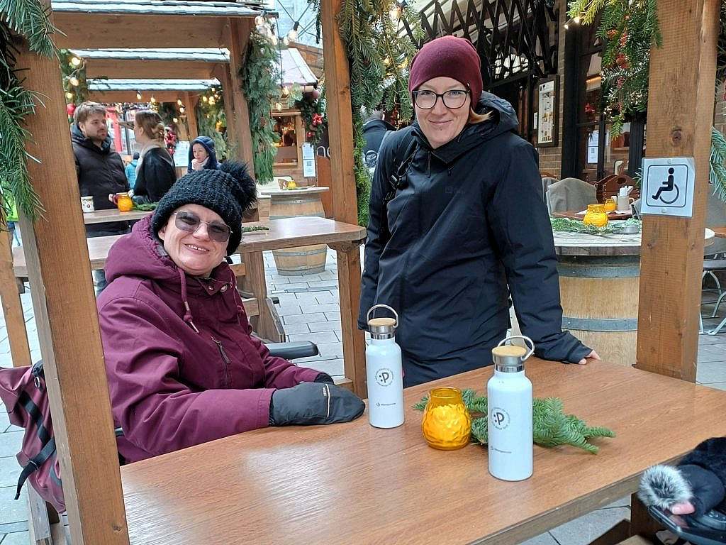 Eine im Rollstuhl sitzende und eine stehende Frau an einem niedrigen Rollstuhlfahrer-Tisch