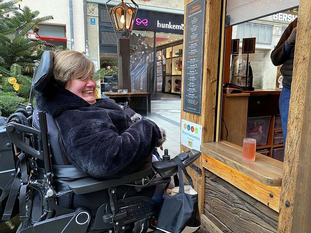 Woman in a wheelchair at a stand in front of a low service area