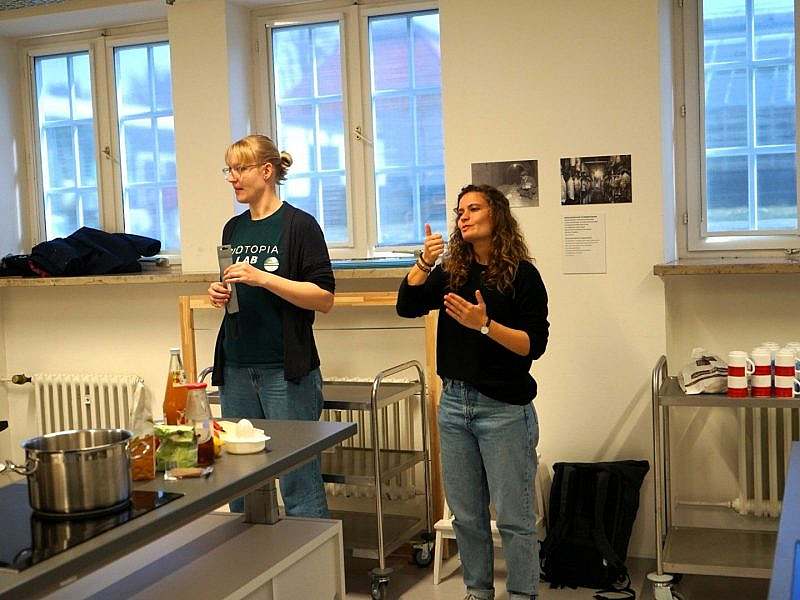 Two women, one of whom is speaking and the other using sign language