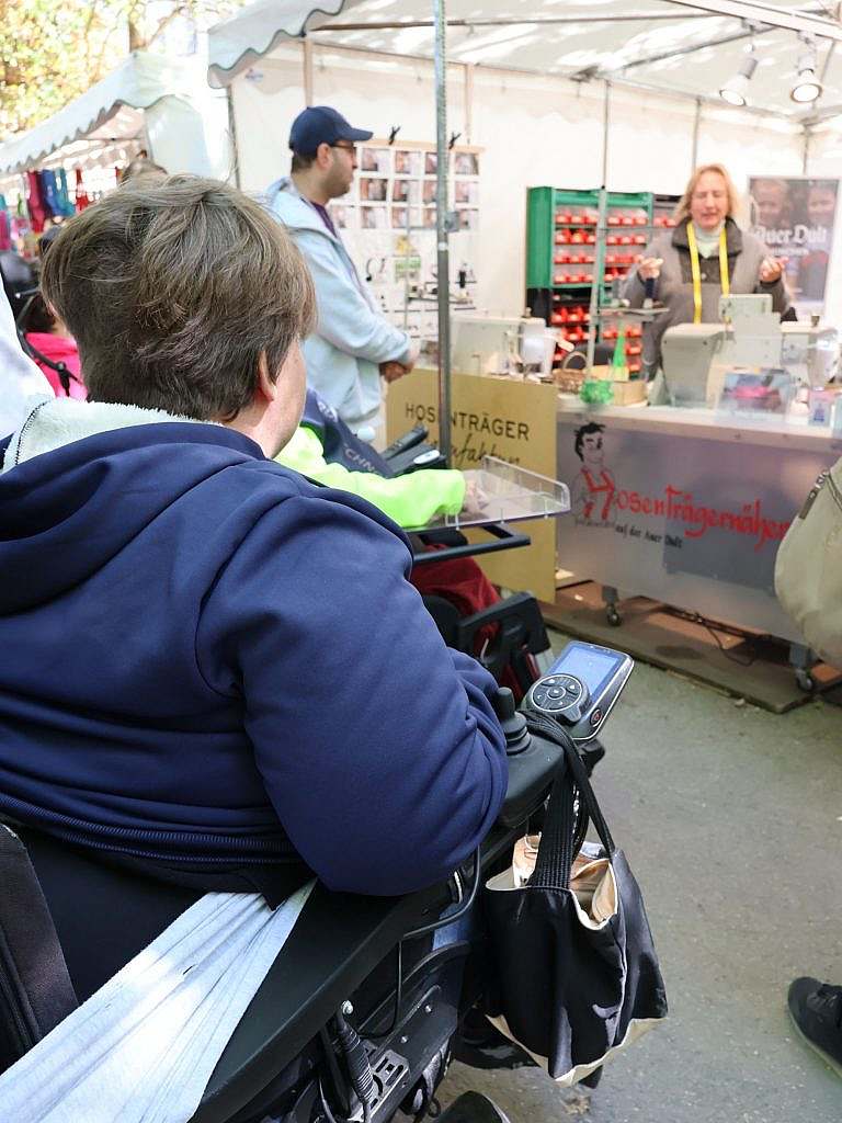 Eine Frau in einem Marktstand erklärt Zuschauern etwas
