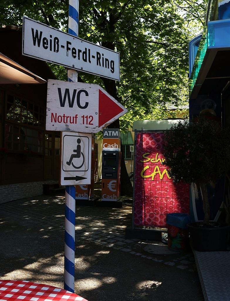 Signage comprising a street sign and directional signs mounted on a white and blue post